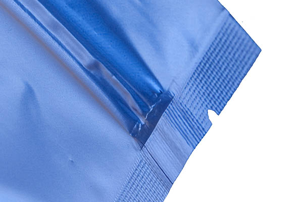Close-up of a blue, metallic-looking pouch showing a sealed edge with a clear plastic zipper closure.
