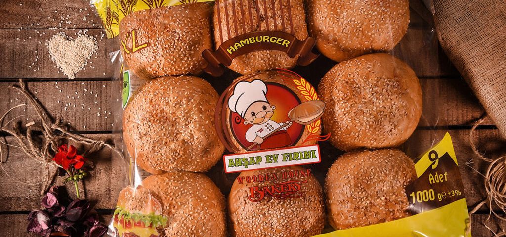 The image shows a package of bread rolls on a wooden table. The package of bread rolls is in the center of the image, with its front