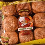The image shows a package of bread rolls on a wooden table. The package of bread rolls is in the center of the image, with its front