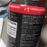 The image shows a hand holding a bottle of CoQ10 supplements, with the focus on the label and the label's background. * The bottle