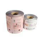 Two rolls of printed packaging film on white background. The larger roll on the left is pink with graphics and text. The smaller roll on the right is white with graphics and text.