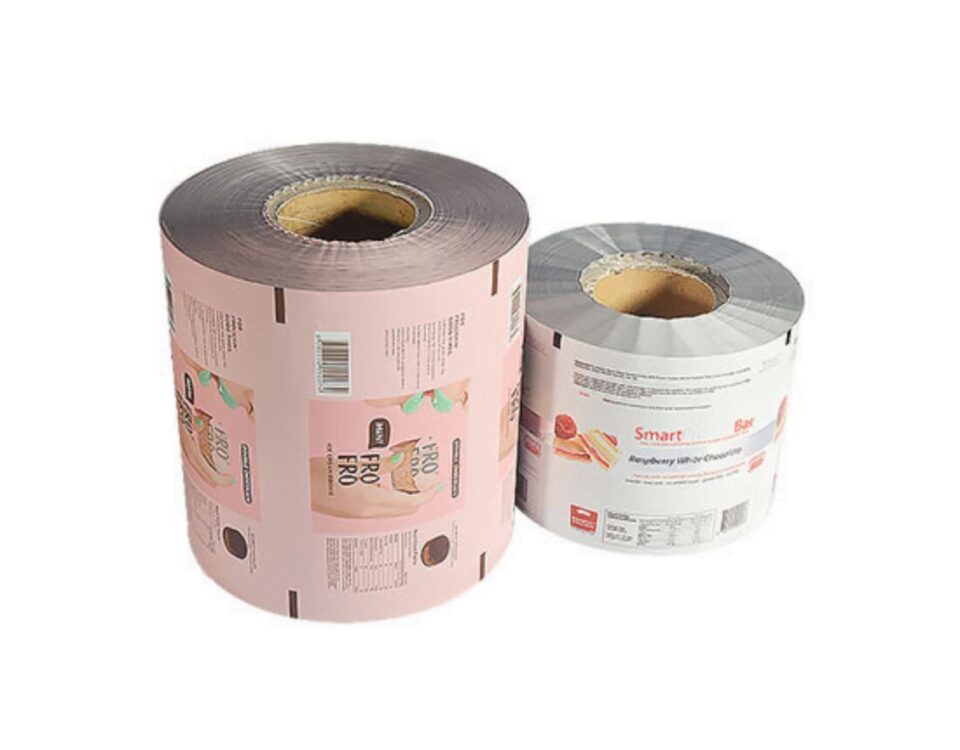 Two rolls of printed packaging film on white background. The larger roll on the left is pink with graphics and text. The smaller roll on the right is white with graphics and text.