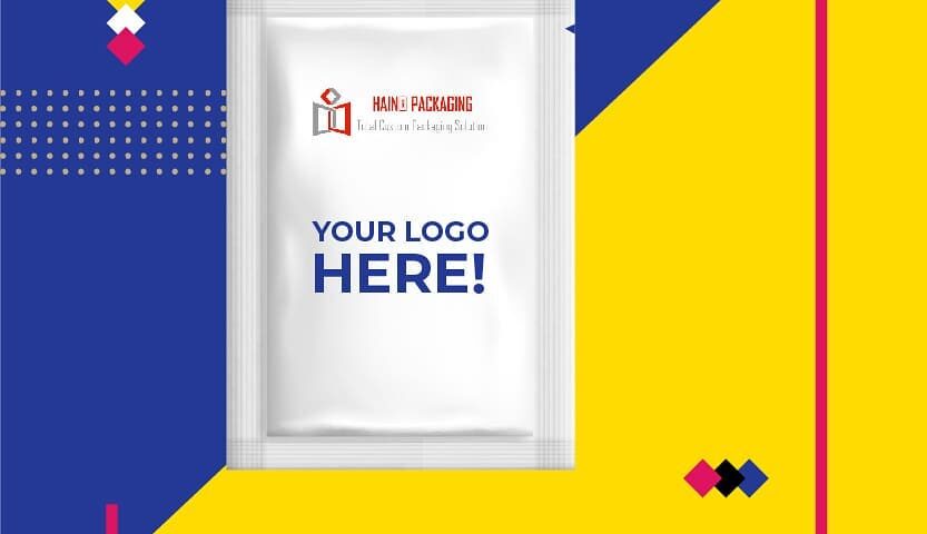 A white, three-side seal sachet bag with "YOUR LOGO HERE!" printed in blue, and a smaller logo above. The sachet is presented on a vibrant blue and yellow background with graphic elements.