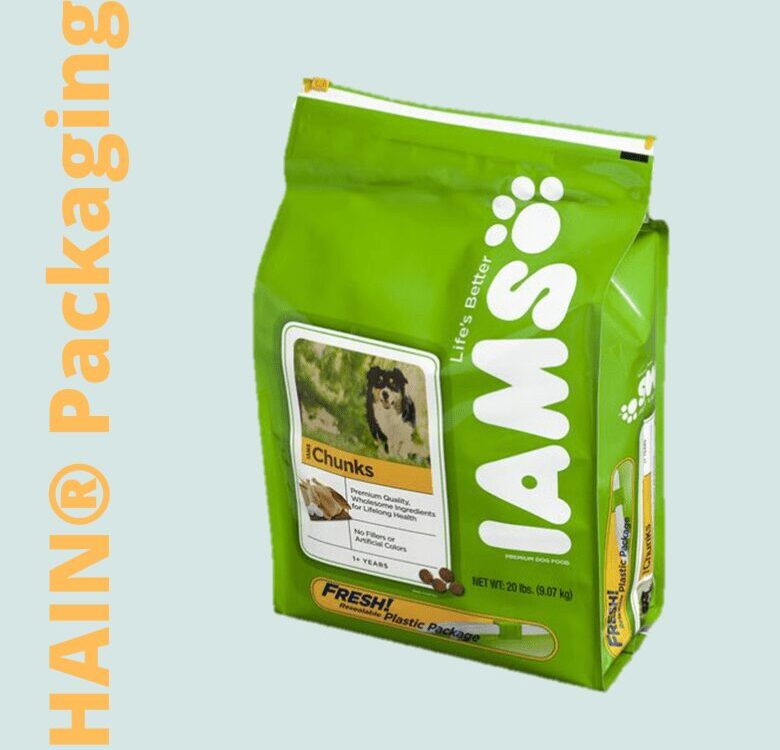 A bright green bag of dog food with a white resealable closure at the top. The front features a label with a picture of a dog, text indicating 'Chunks', and the brand logo 'IAMS' in large white letters with paw prints.