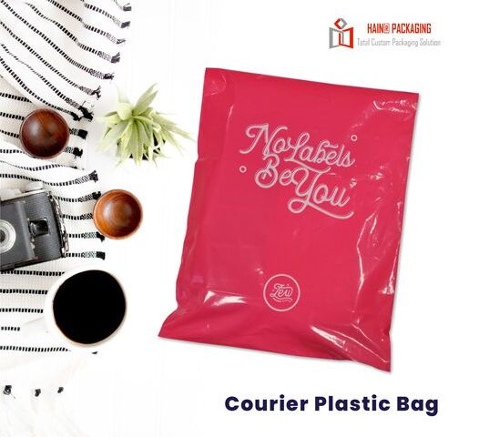 A bright pink courier bag with white text reading 'No Labels Be You' and a circular logo. The bag is shown flat with its flap folded over.