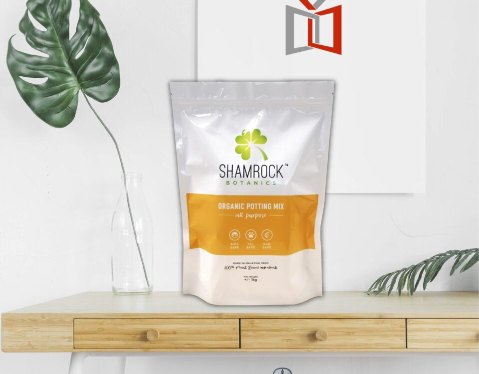A white and orange resealable pouch containing organic potting mix, with a shamrock logo and text indicating it is for all purposes. Icons for kids, pet, and eco safety are visible.