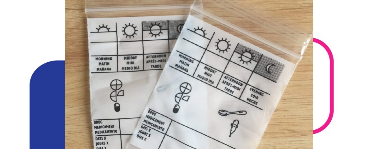 Two clear plastic zip-top bags are shown on a wooden surface. Each bag contains a white insert printed with a grid for tracking medication times (Morning, Midday, Afternoon, Evening) and icons representing drugs, a spoon, and a dropper. Text is printed in multiple languages.
