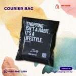 A black courier bag with white text printed on it, placed on a background with watercolor splashes.