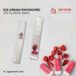 Two clear plastic bags designed for ice cream packaging are displayed. One bag has a label with a strawberry logo and text, while the other features a repeating pattern and a circular label with text and graphics. Sliced strawberries and ice cream bars are arranged nearby.