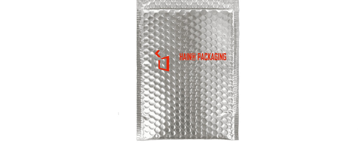 A silver padded mailer envelope with a bubble-lined interior and a peel-off adhesive strip along the top opening. The envelope features a logo and text reading 'HAINER PACKAGING' and 'Custom Packaging Solutions'.
